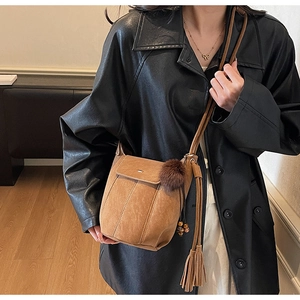 Vista dettagliata della borsa a secchiello vintage marrone opaco con pompon e nappe