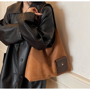 Detailed shot of brown suede tote bag featuring a leather front pocket and magnetic closure