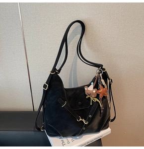 Detail of matte black leather tote bag featuring gold hardware and bear charm