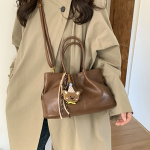 Détail du sac à main en cuir marron foncé avec pendentif ours et bandoulière réglable