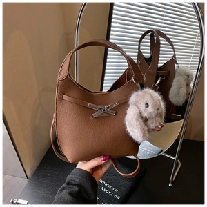 Detail of brown bucket bag featuring a gold cross-lock buckle and cute plush rabbit charm