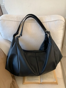 Retro black litchi grain hobo bag with pleated texture on a soft beige fabric background