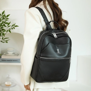 Detail of black lychee grain leather backpack with silver rabbit logo and metal zippers