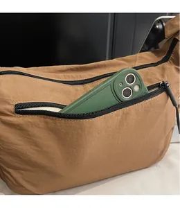 Tan nylon crescent bag showing front zipper pocket with smartphone storage detail