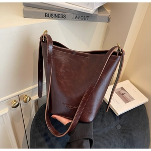 Detail of dark brown bucket bag with smooth leather texture and embossed fashion text