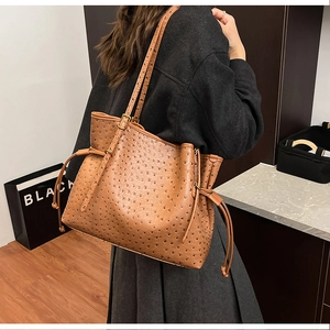 Close-up of brown ostrich-embossed leather tote bag with drawstring side detail