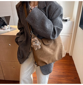Brown suede tote bag detail with cute plush bear charm and vintage flip cover design