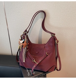 Detail of burgundy leather tote featuring litchi texture and cute bear charm pendant