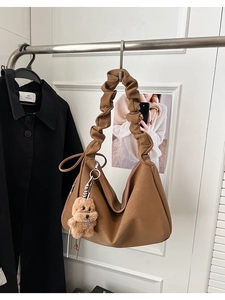 Detailed view of brown lychee grain PU tote bag with ruffled handle and plush puppy charm