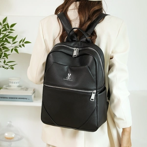 Detail of black pebbled leather backpack showing silver rabbit logo and metal zippers
