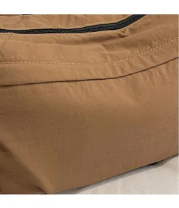 Detail view of brown nylon fabric showing neat beige stitching and zipper closure
