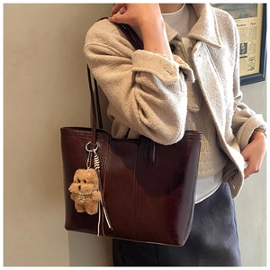 Detail of dark brown tote bag in glossy synthetic leather with cute plush bear charm