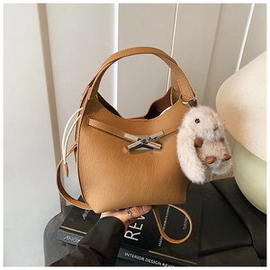 Close-up of caramel brown pebble leather bucket bag with silver X-lock and plush bunny charm