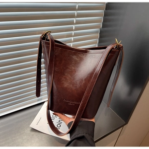 Detail view of vintage dark brown bucket bag featuring textured leather and adjustable strap