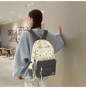 Détail du sac à dos scolaire en nylon avec motif étoilé et poche zippée grise élégante