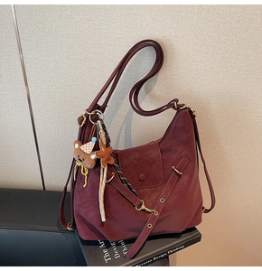 Detail of burgundy pebbled leather texture with bronze hardware and cute bear charm