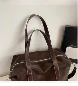 Detail of sturdy double handles and white stitching on a dark brown travel tote bag