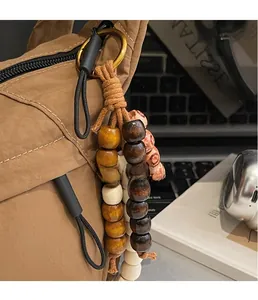Close-up of vintage wooden beads and tassel charm on a nylon handbag shoulder strap