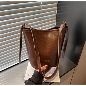 Close-up of a dark brown bucket bag with textured faux leather and gold metal hardware