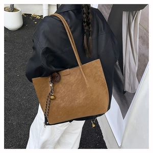 Detail of vintage brown suede tote bag with plush charm and golden bell accessory