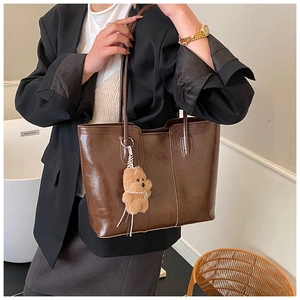 Macro detail of dark brown leather tote bag texture with cute plush dog charm