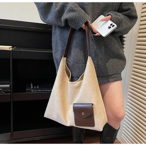Dettaglio della borsa tote in pelle scamosciata beige con manici in pelle marrone e tasca
