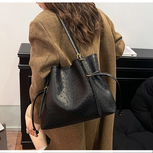 Detail of black ostrich embossed tote bag on shoulder with autumn wool coat