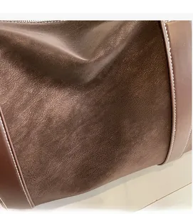 Detail of premium brown leather texture with precise white contrast stitching on shoulder bag