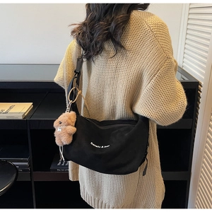 Detail of black large-capacity crossbody bag with branding and cute bear charm
