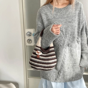 Close-up of a French style woven bucket bag featuring a cute mushroom charm accessory