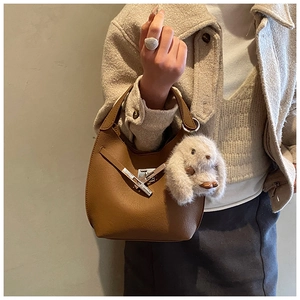 Brown leather bucket bag detail with silver buckle and plush rabbit charm on model