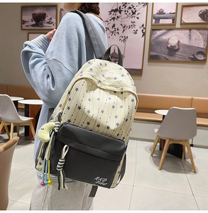 Détail d'un sac à dos scolaire en nylon avec motifs étoiles et pendentif lune en peluche