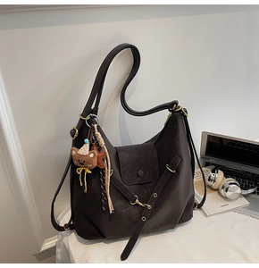 Detail view of large dark brown leather tote bag with flap closure and cute bear charm