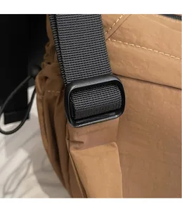 Close-up of adjustable black buckle and durable nylon strap on a brown shoulder bag