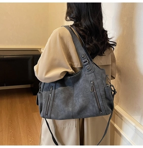Detail of blue textured leather tote bag with vertical zippers shown on a model's back