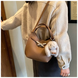 Detail of brown lychee grain leather bucket bag with silver clasp and plush bunny charm