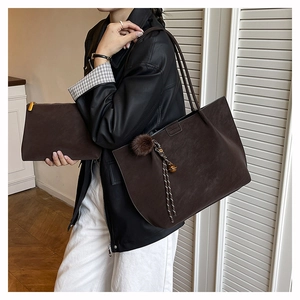 Detail of dark brown leather tote bag and matching pouch with decorative charm