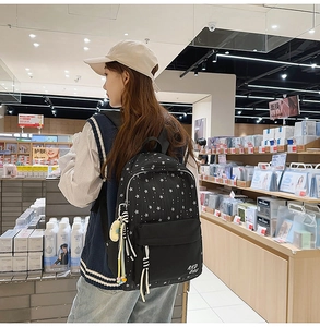 Détail d'un sac à dos en nylon noir à motif d'étoiles avec un pendentif animal mignon