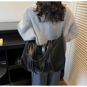 Detail of black large tote bag with white contrast stitching and adjustable shoulder strap
