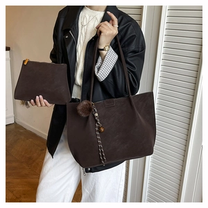 Detail of dark brown matte leather tote bag with small matching pouch and fuzzy charm