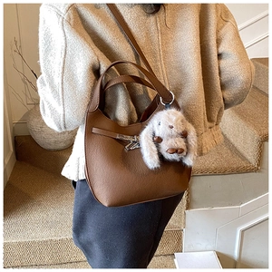 Detail of brown litchi leather hobo bag with silver buckle and plush bunny charm