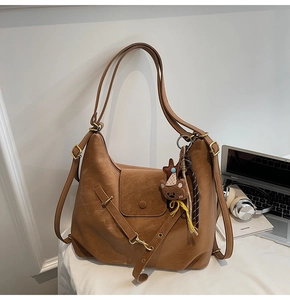 Detailed view of the brown leather tote bag texture with cute bear charm and tassel