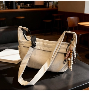 Detail of minimalist nylon shoulder bag with adjustable strap and colorful wood bead tassel