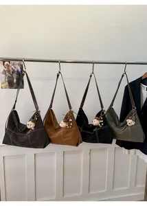 Detail view of large soft leather tote bag with contrast stitching and bear charm