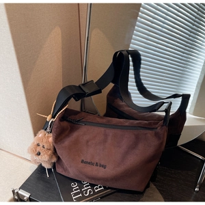 Macro detail of dark brown faux suede shoulder bag with Banaiu & bag logo and dog charm