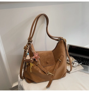Detail of a brown faux leather tote bag with gold metal buckles and cute plush charms
