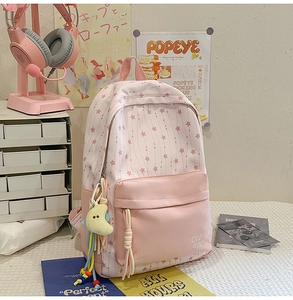 Détail d'un sac à dos en nylon rose à motifs d'étoiles avec un pendentif lune jaune