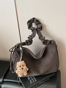 Dark brown faux leather tote bag with ruched handle and plush puppy pendant accessory