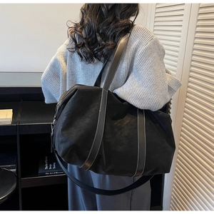 Detail of large black travel tote featuring contrast white stitching and detachable strap