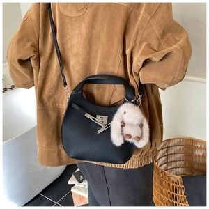Detail of black hobo handbag with silver hardware and a beige plush bunny charm